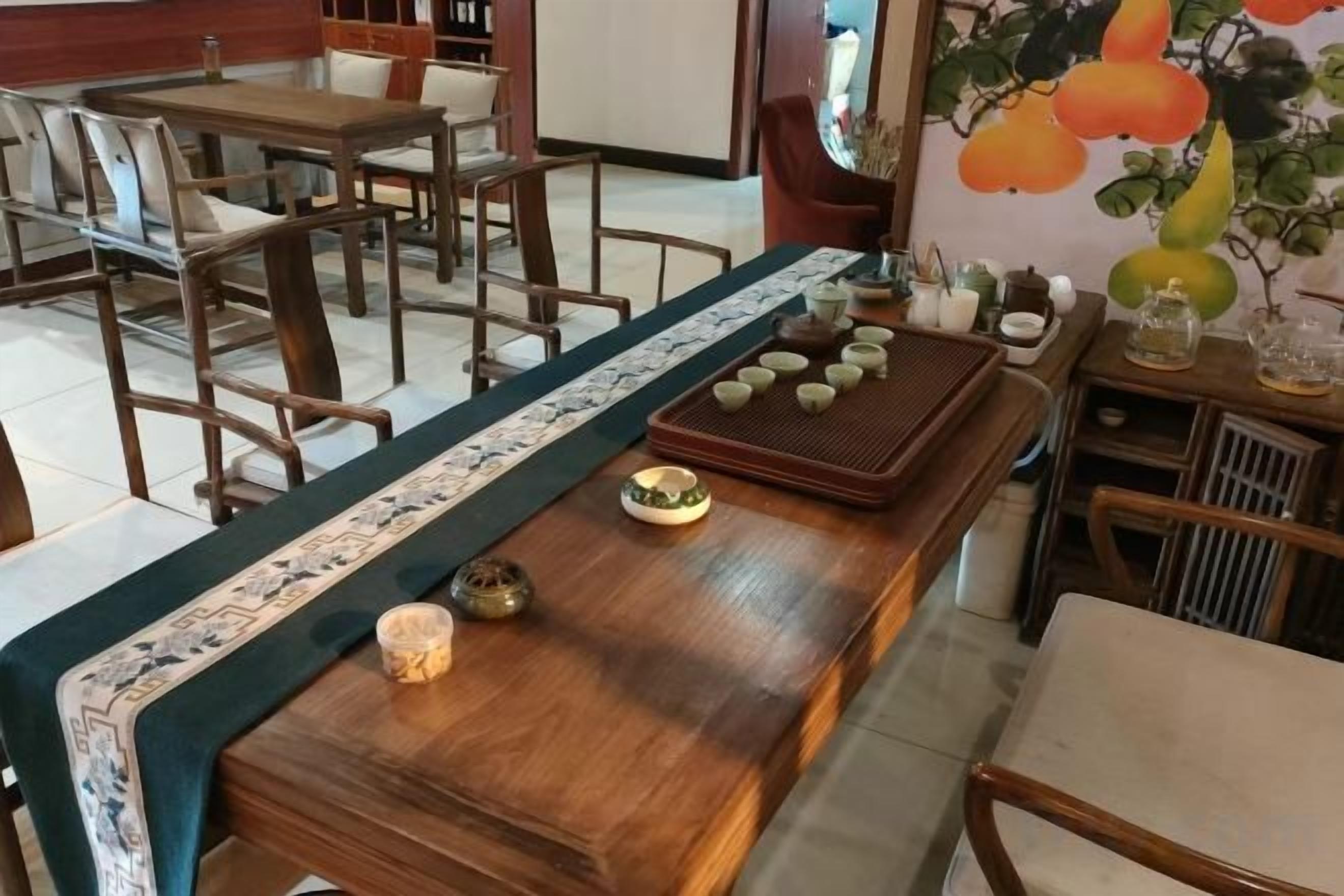 A dining area with a long wooden table, chairs, and a decorative wall with fruit paintings.
