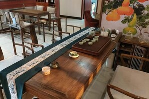 A dining area with a long wooden table, chairs, and a decorative wall with fruit paintings. - Jiaqi Landscape Hotel (Chizhou)