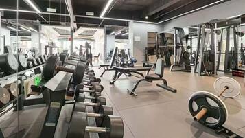 A gym with various exercise equipment, mirrors, and weightlifting stations.