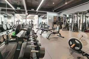 Een sportschool met diverse fitnessapparaten, spiegels en krachtstations.