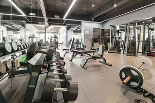 A gym with various exercise equipment, mirrors, and weightlifting stations.