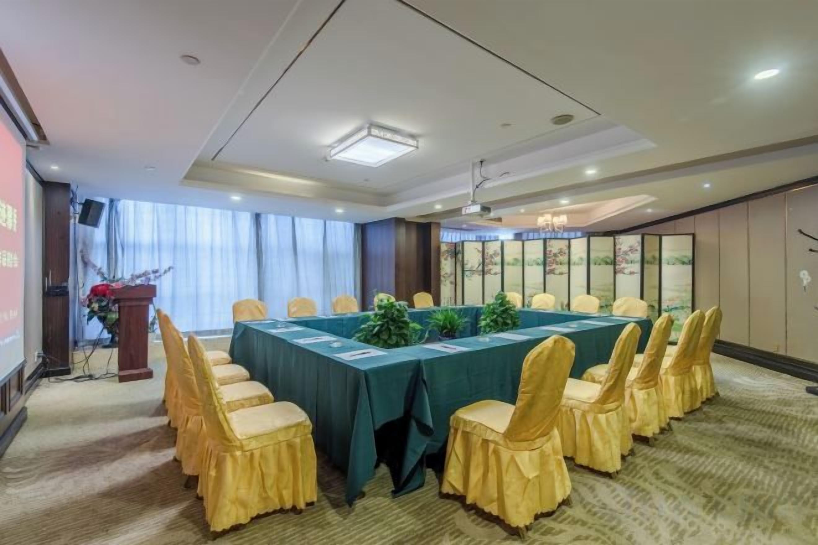 A conference room with a long table, chairs, a podium, and a projector screen.