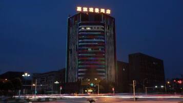 A high-rise building with illuminated windows and a sign at the top.