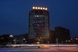 A high-rise building with illuminated windows and a sign at the top.