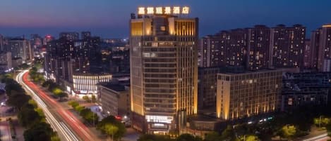 A high-rise hotel with multiple floors, surrounded by a cityscape at dusk.