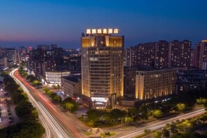 A high-rise hotel with multiple floors, surrounded by a cityscape at dusk. - Jiaqi Landscape Hotel (Chizhou)
