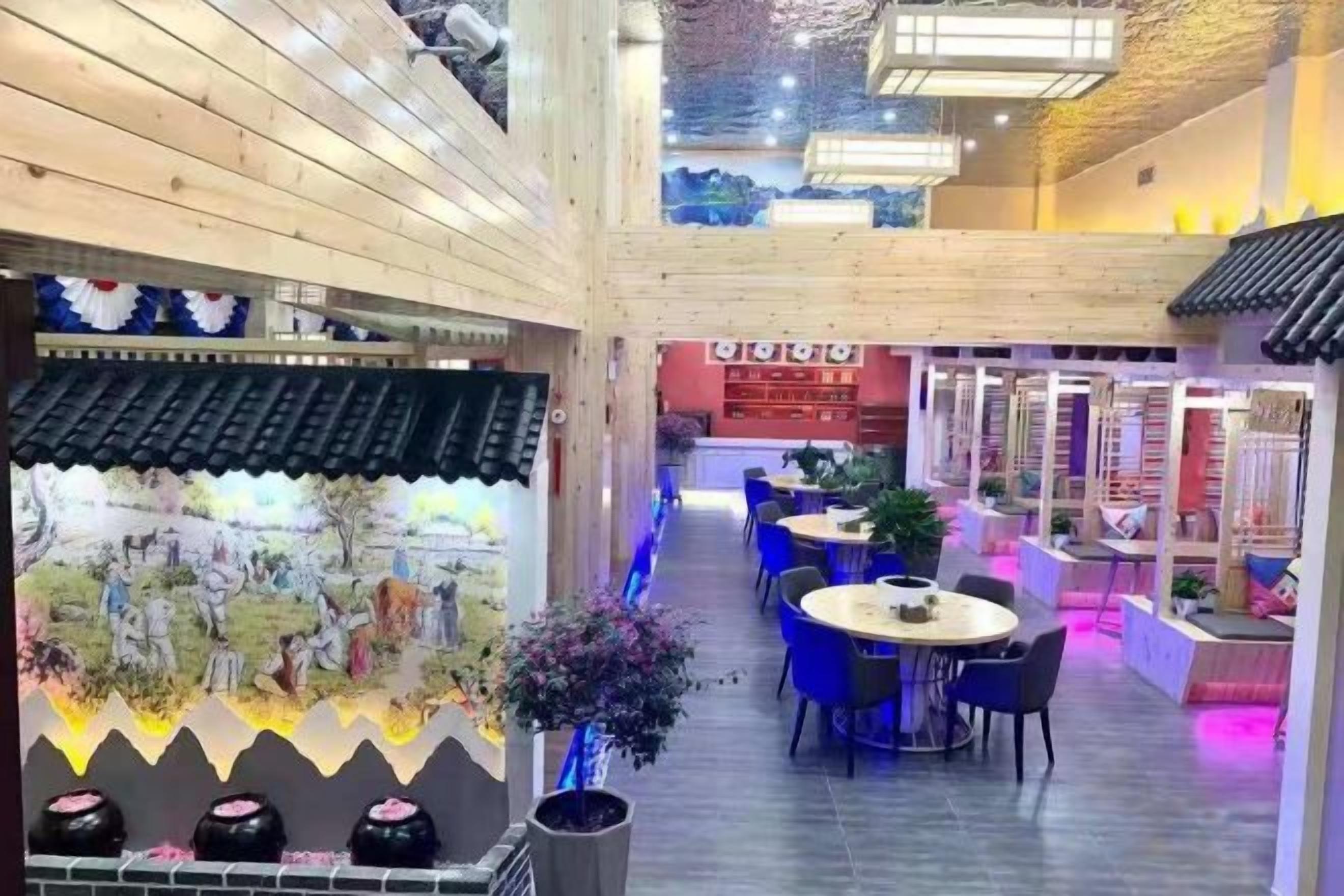 Un restaurante con techo alto, vigas de madera y un pasillo central. Mesas y sillas están dispuestas a lo largo de los laterales.