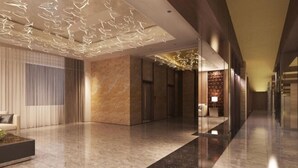 A modern hotel lobby with a marble floor, a seating area with a sofa and a coffee table, and a decorative light fixture on the ceiling. - Royal Hot Spring Hotel (Baishan)