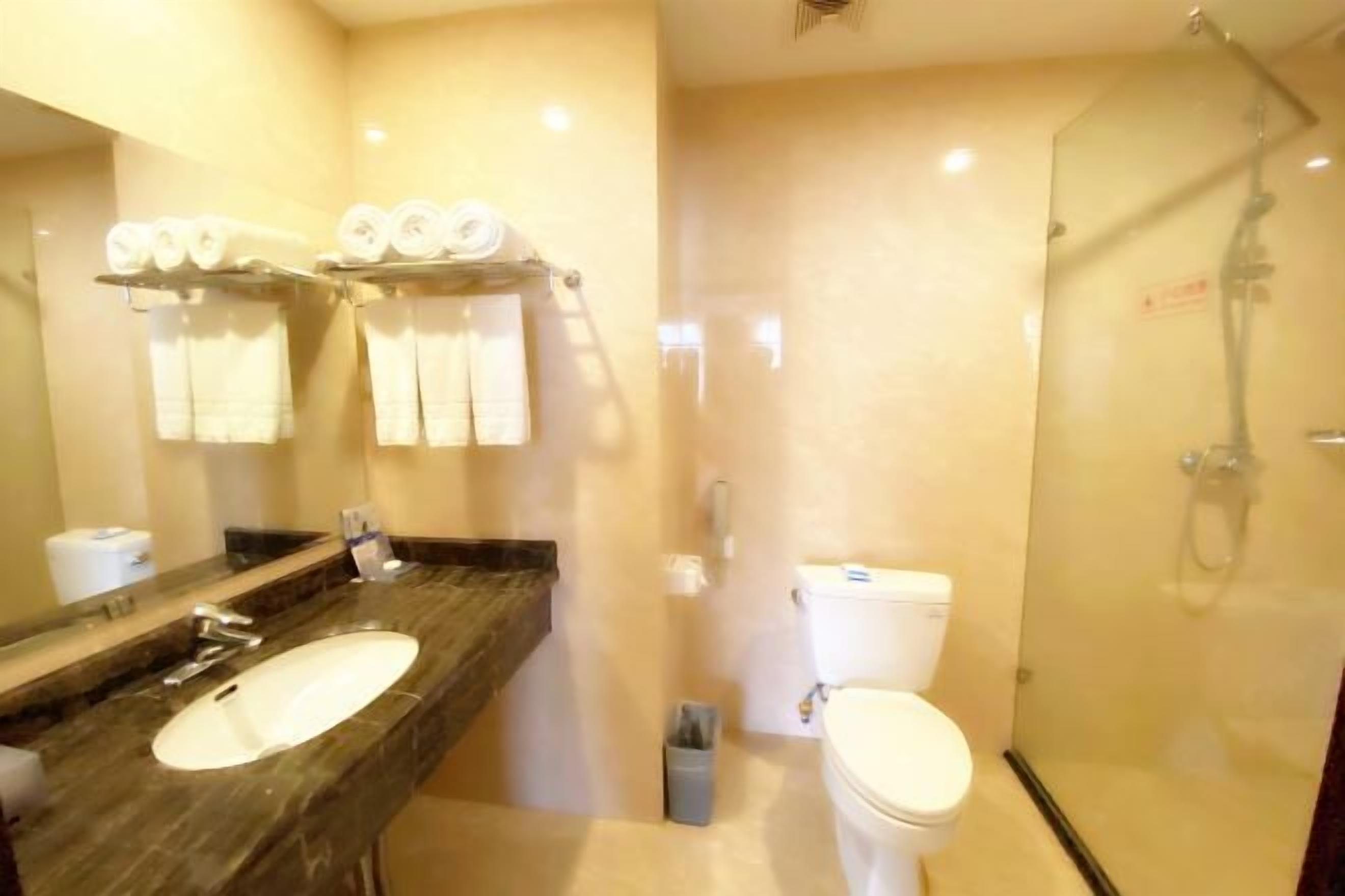 Un baño con lavamanos de mármol, inodoro y ducha con cerramiento de vidrio.