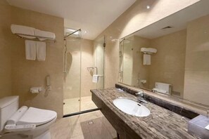A modern bathroom with a marble sink, a glass-enclosed shower, and a toilet.