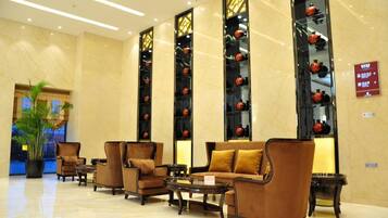 A lobby with seating arrangements, a large potted plant, and decorative vases on shelves.