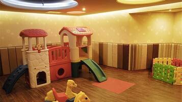 A children's play area with a slide, climbing structures, and soft play toys.