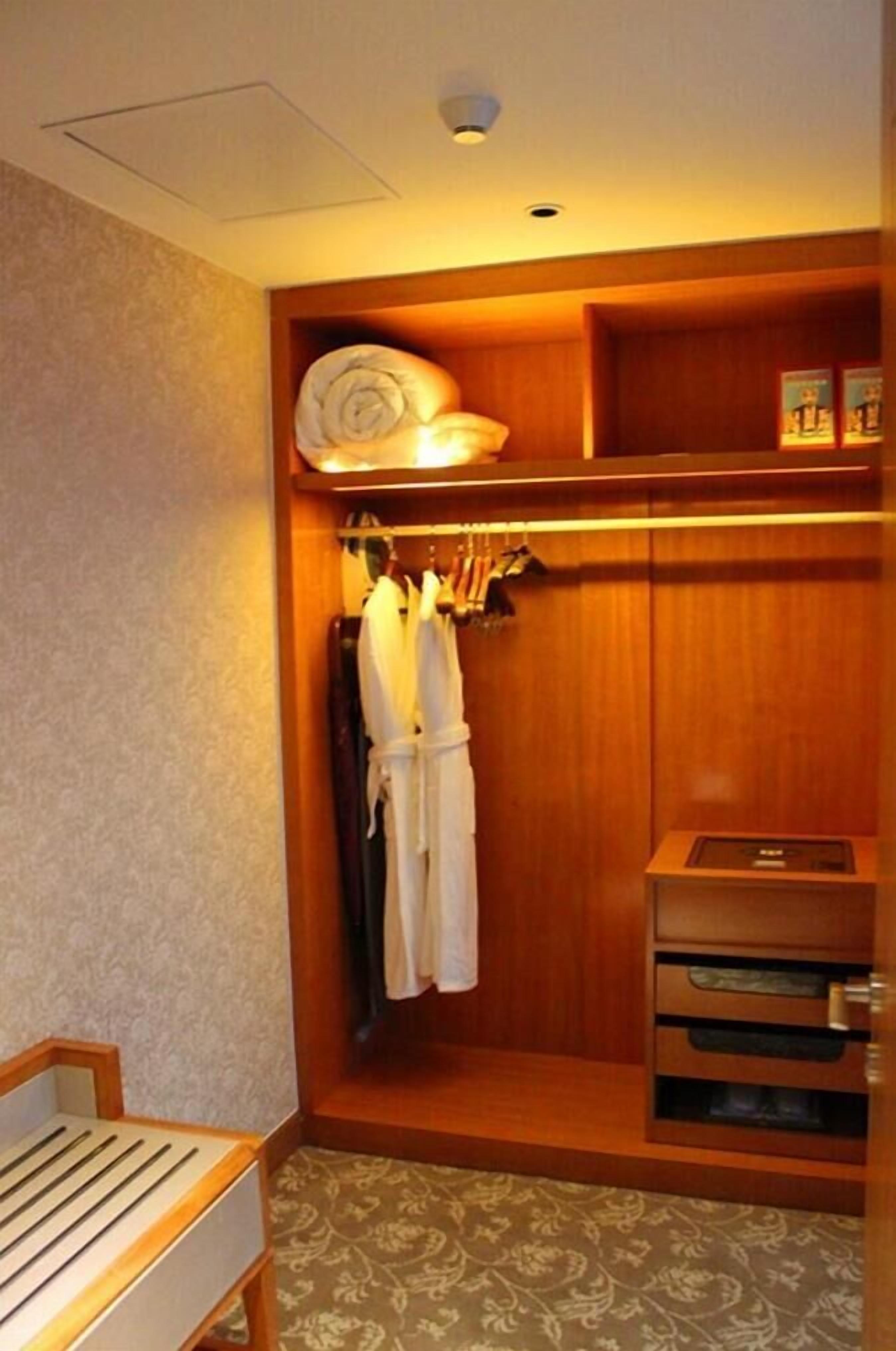 Una habitación de hotel con un armario de madera, una cama y una pequeña mesa.