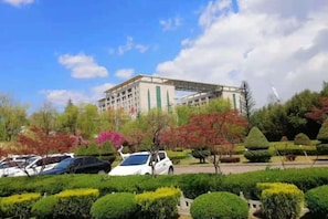 A hotel with a large building, surrounded by well-maintained gardens and parked cars. - Longshan Hotel (Handan)