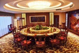 Un salón de conferencias con una mesa redonda, sillas y una araña.