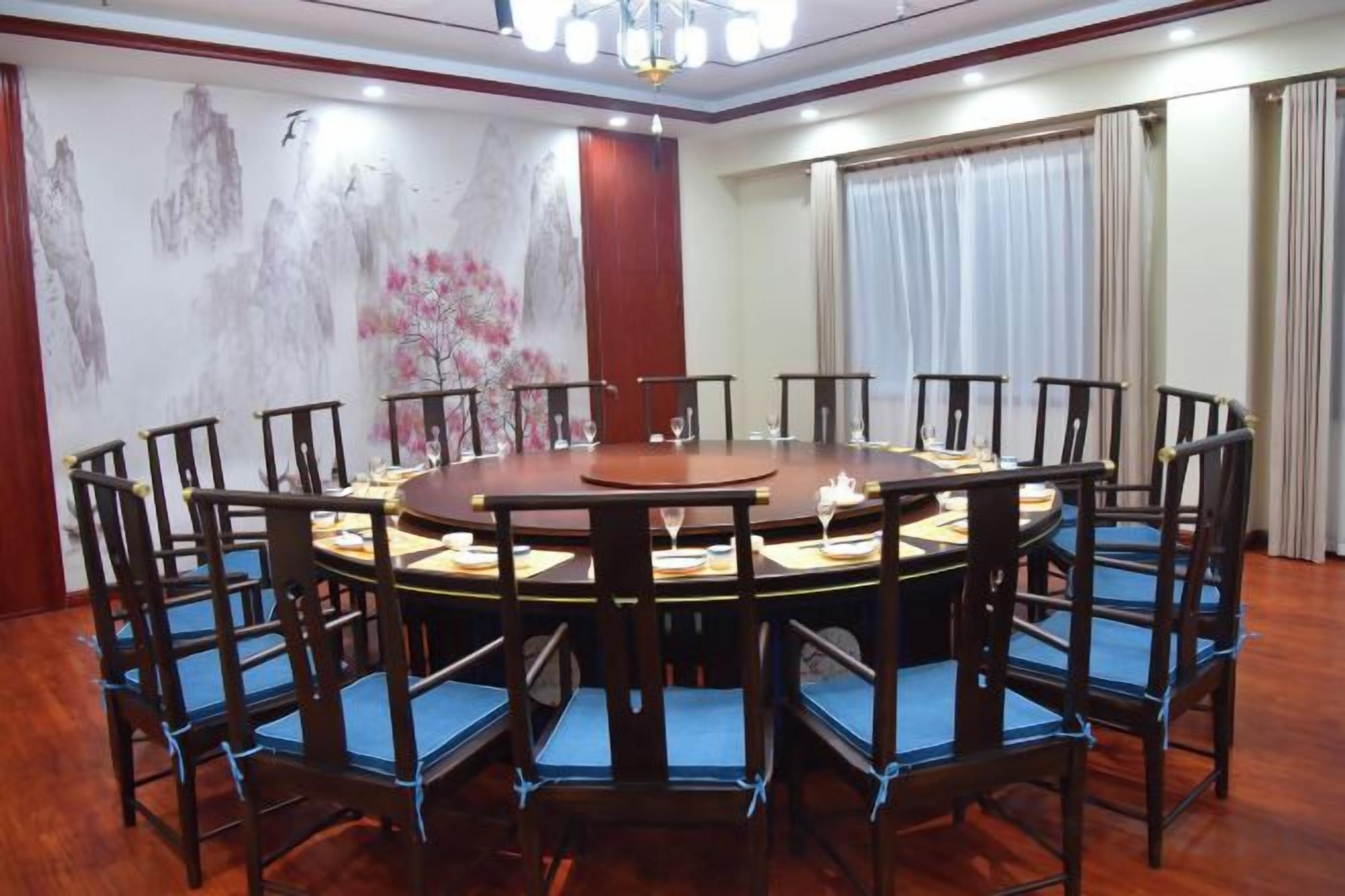 Un salón de conferencias con una mesa redonda, sillas y un candelabro.