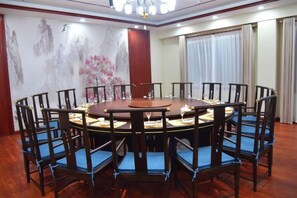 Een vergaderzaal met een ronde tafel, stoelen en een kroonluchter.
