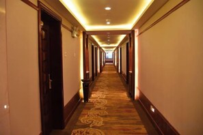 A hotel hallway with carpeted floors, wooden doors, and overhead lighting. - Longshan Hotel (Handan)