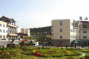 Un edificio de varios pisos con un patio central, rodeado de vegetación y una zona de estacionamiento.