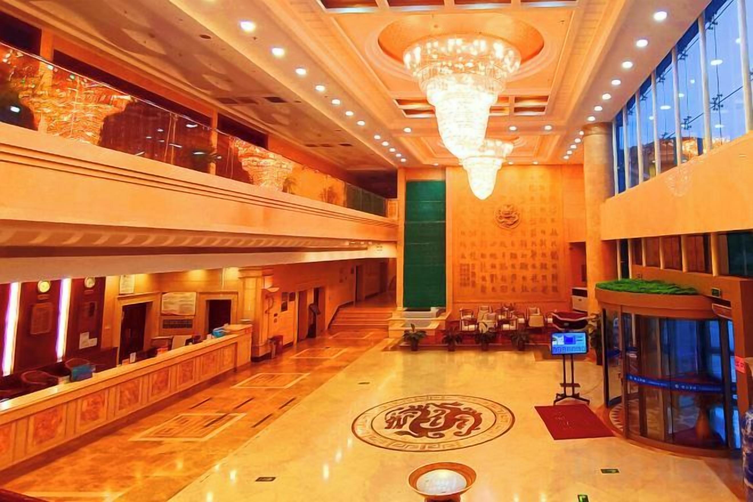 Un vestíbulo de hotel con mostrador de recepción, candelabro y un amplio ventanal.