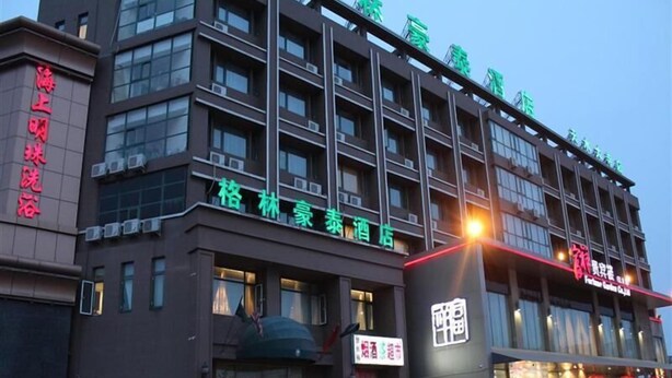 A multi-story hotel with a modern design, featuring a prominent entrance with glass doors and a sign indicating a restaurant on the ground floor. - GreenTree Inn Tianjin Xiqin Development District Dasi Meijiang Exhibition Center Hotel (Tianjin)