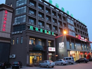 Ein mehrstöckiges Hotel mit modernem Design, das einen markanten Eingang mit Glasüren und eine Schilderung eines Restaurants im Erdgeschoss aufweist.
