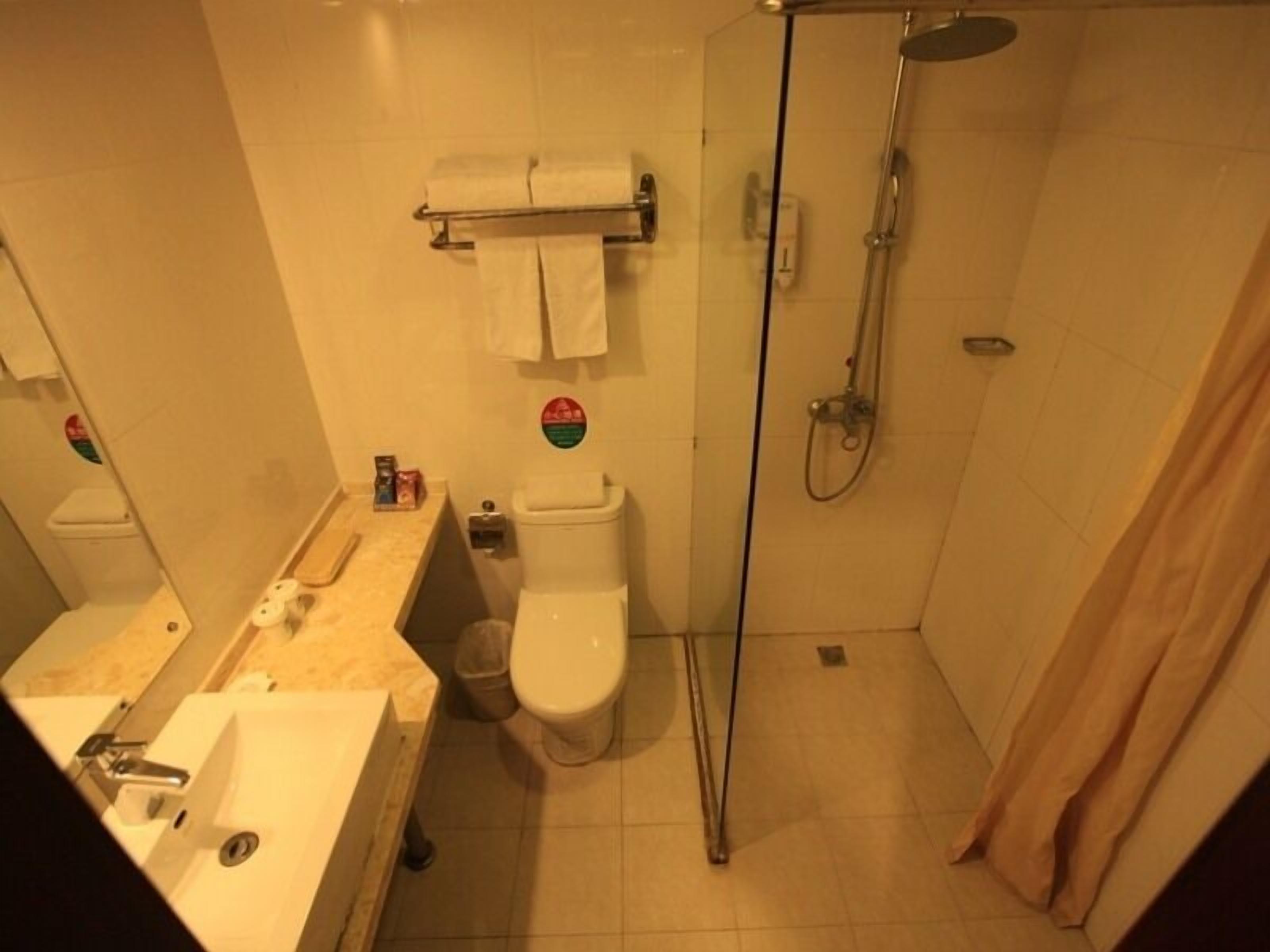 A small bathroom with a toilet, sink, and shower.