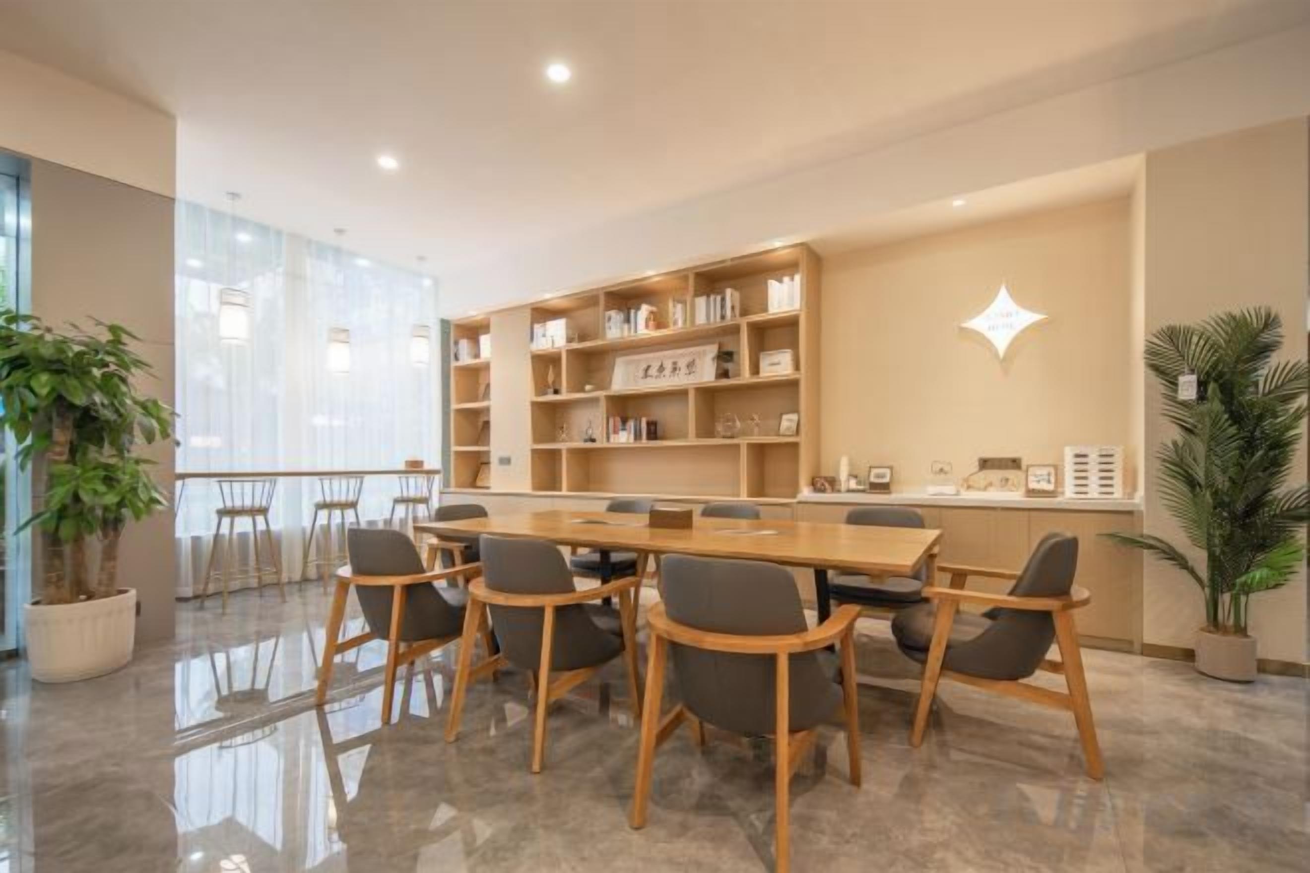 A conference room with a long table and chairs, a bookshelf, and a modern light fixture.