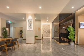 A modern hotel lobby with a reception desk, seating area, and a marble wall with a mountain painting. - Jinjiang Inn (Lin'an Qianwang Street) (Hangzhou)