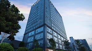 A modern high-rise building with a glass facade, surrounded by trees and other buildings. - Art Hotel (Shenzhen)