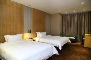 Habitación de hotel con dos camas, un sofá, un escritorio y una cortina.