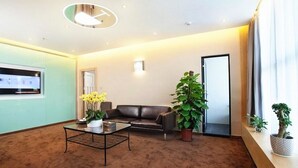 A modern hotel lobby with a leather sofa, a coffee table, and potted plants. - Art Hotel (Shenzhen)