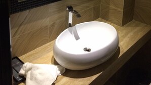 A bathroom with a round white sink, a mirror, and a towel rack. - Art Hotel (Shenzhen)