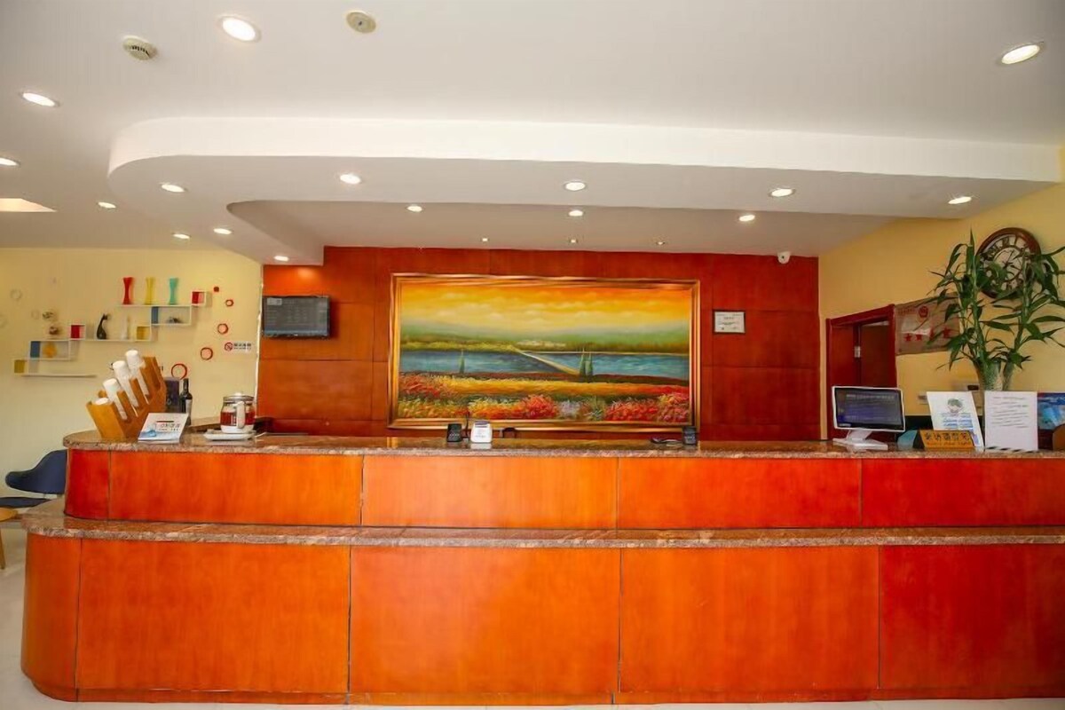 A reception desk with a painting above it, a clock, and a computer monitor.