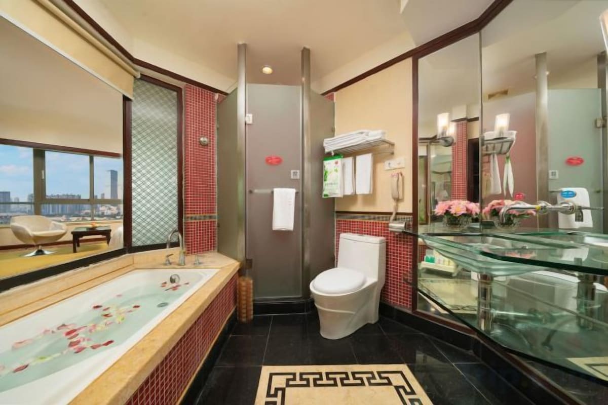 A modern bathroom with a large bathtub, toilet, and glass-enclosed shower area.