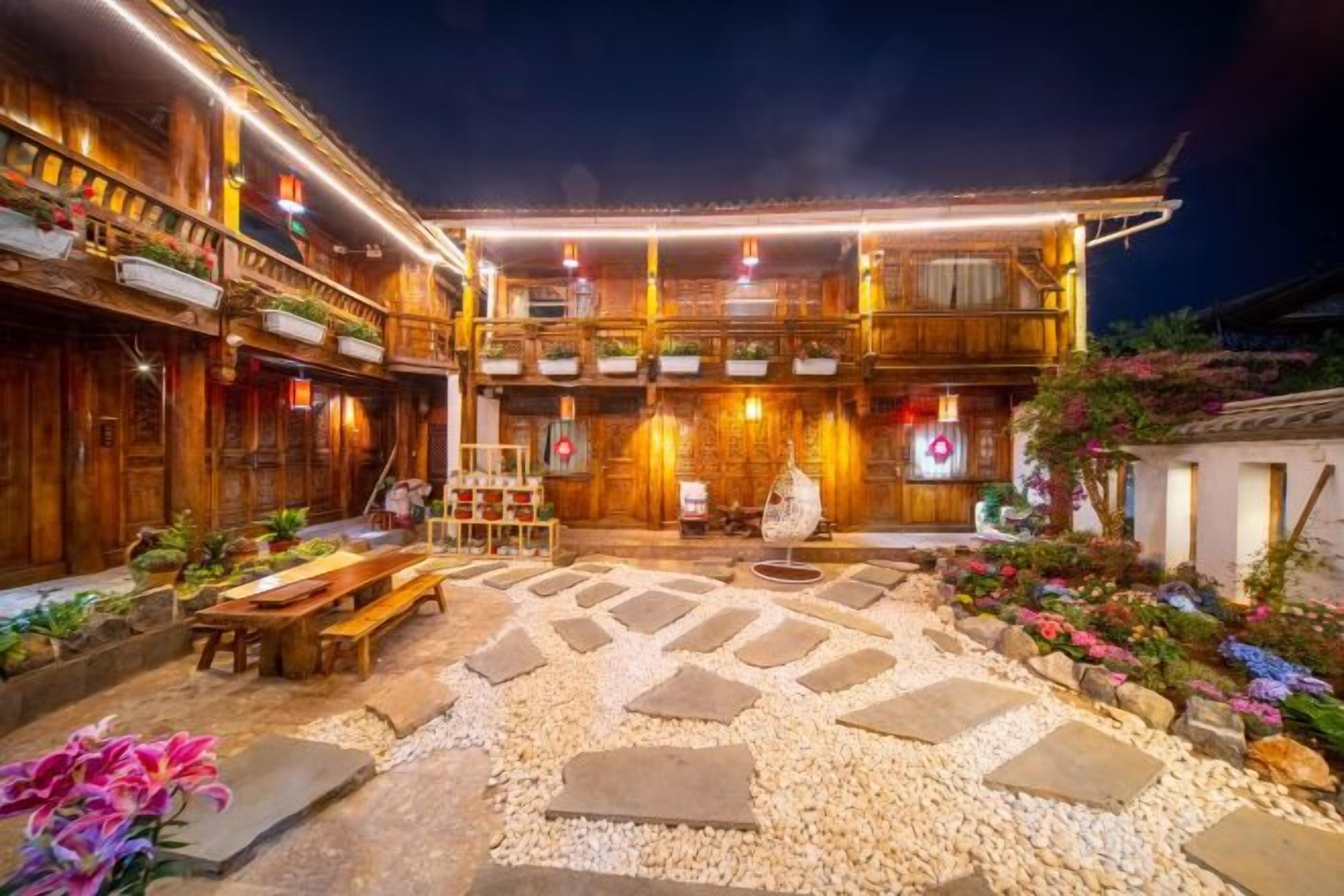A traditional wooden building with a courtyard, stone pathway, and potted plants.