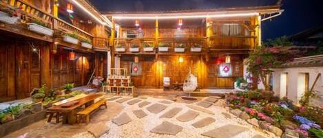 A traditional wooden building with a courtyard, stone pathway, and potted plants.