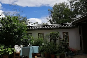 Un bâtiment traditionnel avec un toit en tuiles et une cour intérieure agrémentée de plantes en pot et d’une table.