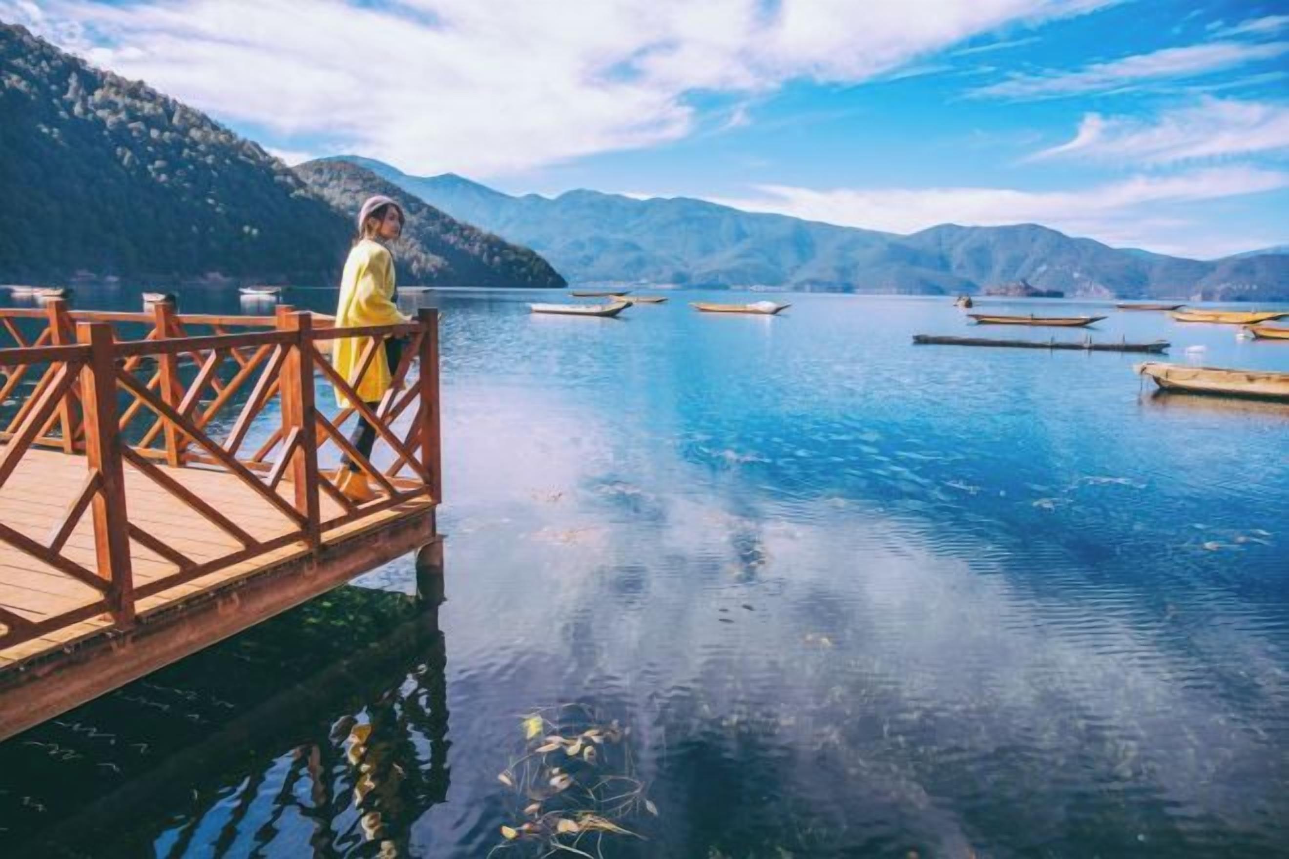 A wooden dock extending into a calm lake with mountains in the background.
