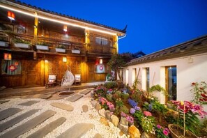 A traditional building with a balcony, stone steps, and a garden with flowers.
