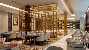 A modern dining area with multiple tables and chairs, a decorative wooden partition, and a chandelier. - Holiday Inn Beijing Airport Zone by IHG (Beijing)