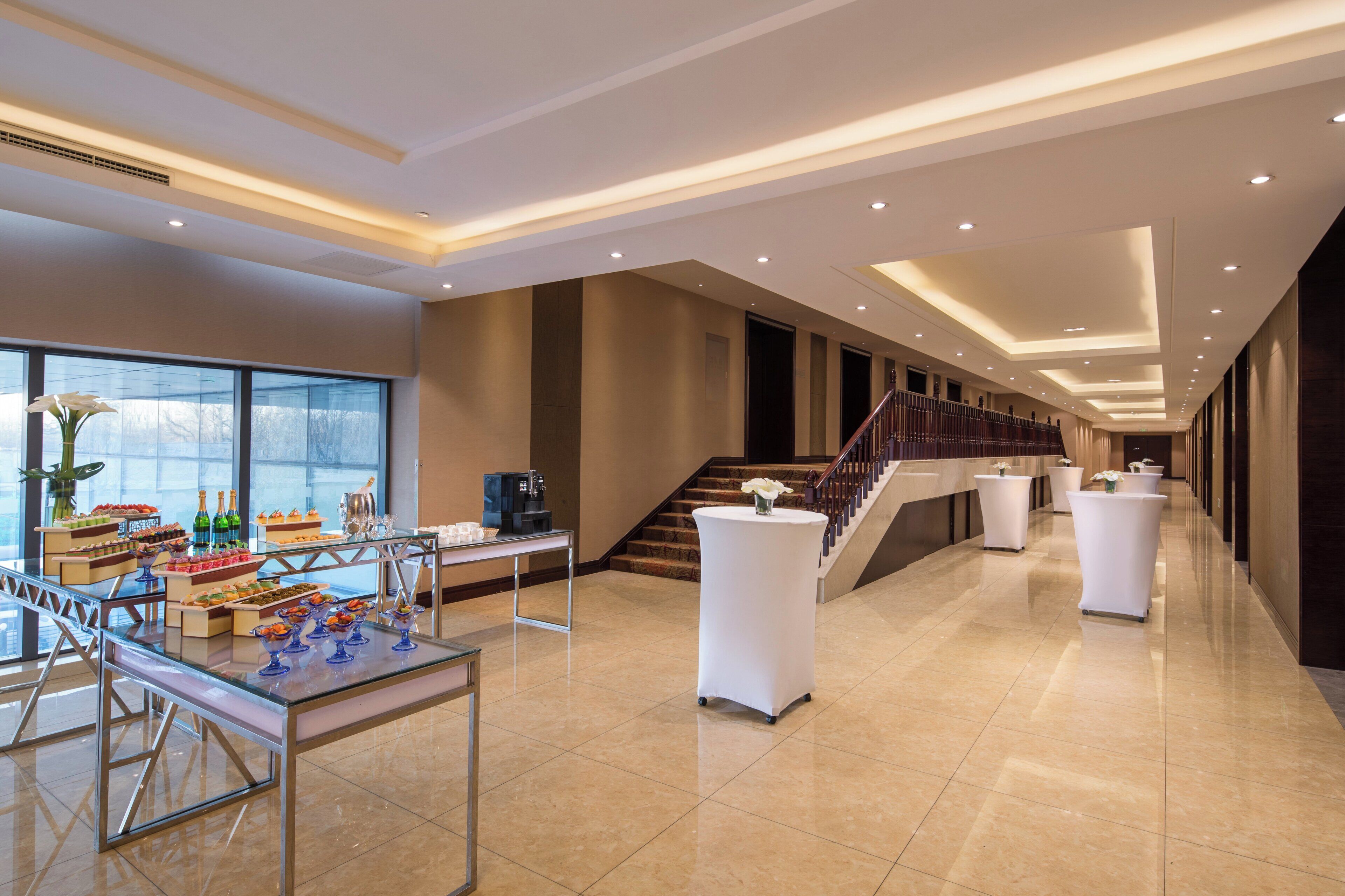 A spacious lobby with a reception desk, a buffet area, and a staircase leading to upper floors.