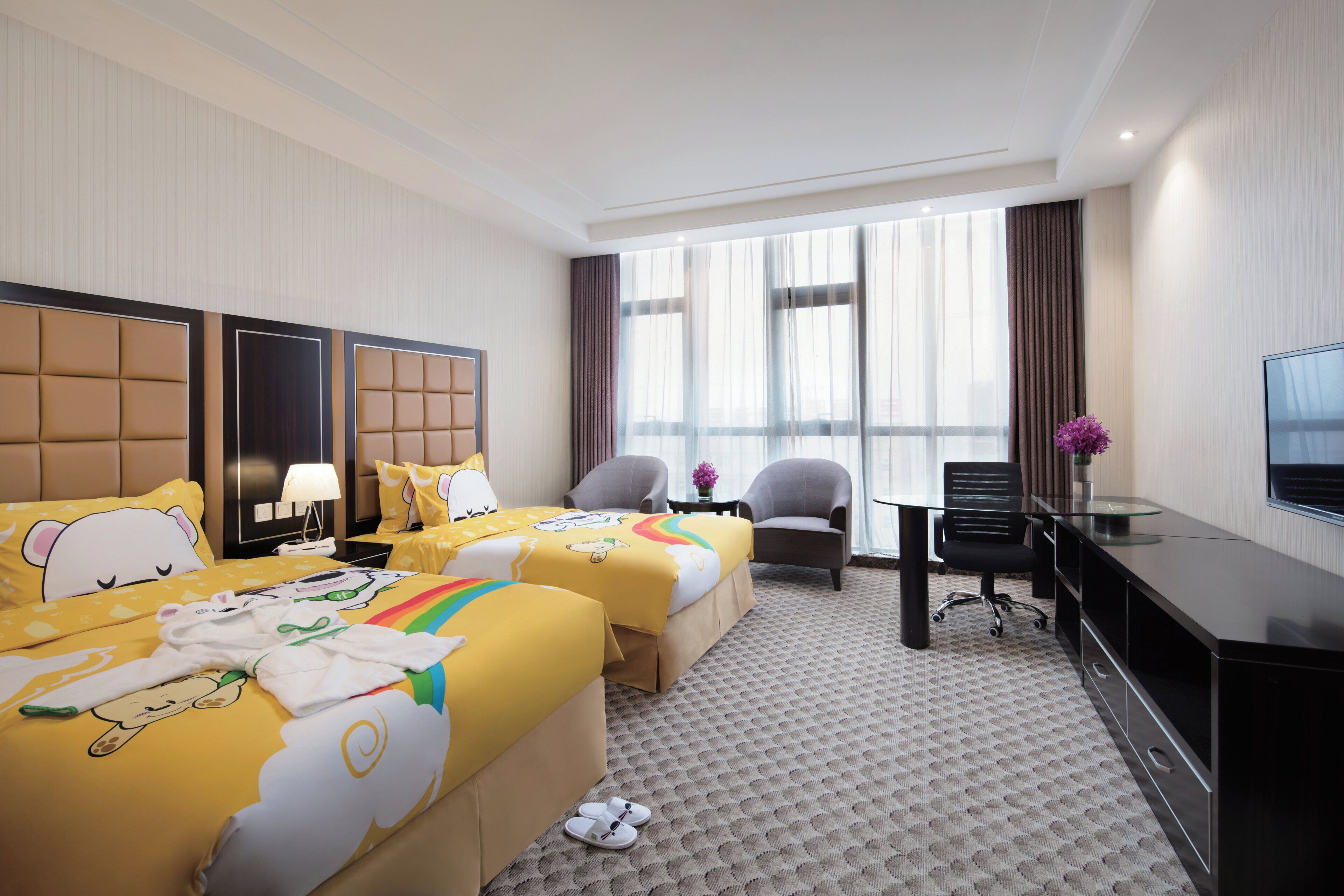 Habitación de hotel con dos camas, un escritorio, una silla y un televisor.