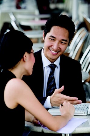 A man and a woman sitting at a table with a laptop, engaged in a conversation. - Holiday Inn Beijing Airport Zone by IHG (Beijing)