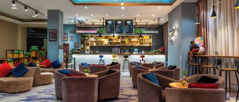 A hotel lobby with sofas, a bar area, and a patterned carpet.