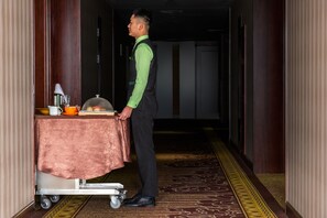 A hotel corridor with a service cart, a table with a cloth, and a person in a uniform. - Holiday Inn Beijing Airport Zone by IHG (Beijing)