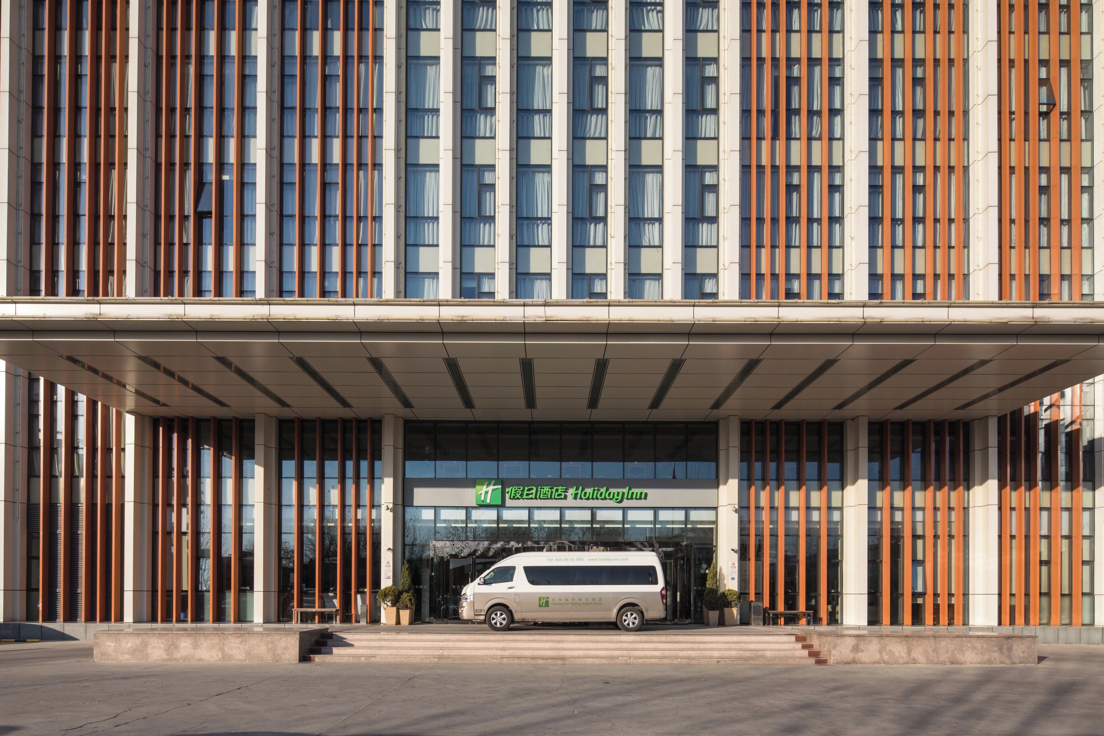 A modern building with a large entrance and a van parked in front.