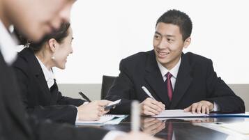 Una reunión de negocios con dos personas en una mesa, una sosteniendo un bolígrafo y la otra un dispositivo móvil.