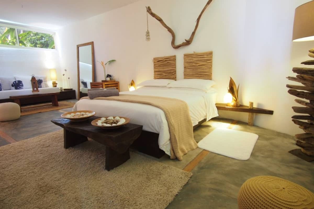 Un dormitorio con cama, mesitas de noche, un espejo y una ventana.