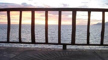 A wooden railing overlooking a body of water during sunset.